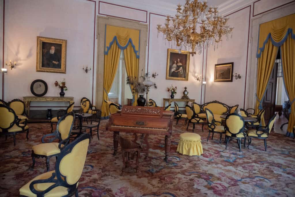 Yellow chars and stools around a piano in an elaborate palace room