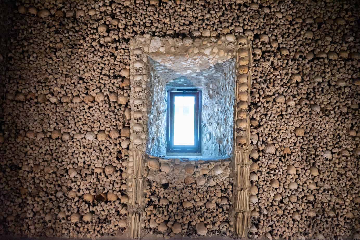 a window surrounded by skulls and bones in the chapel of bones in evora