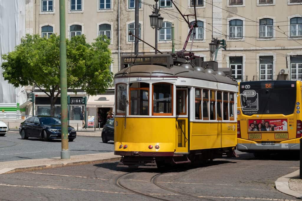 Yellow and White Tram travels through streets in Lisbon Portugal