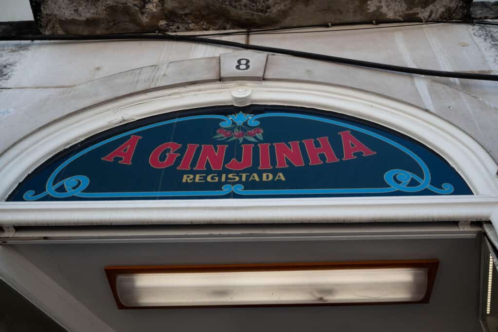 A Ginginha written on a half circle window in red letters with a blue background.