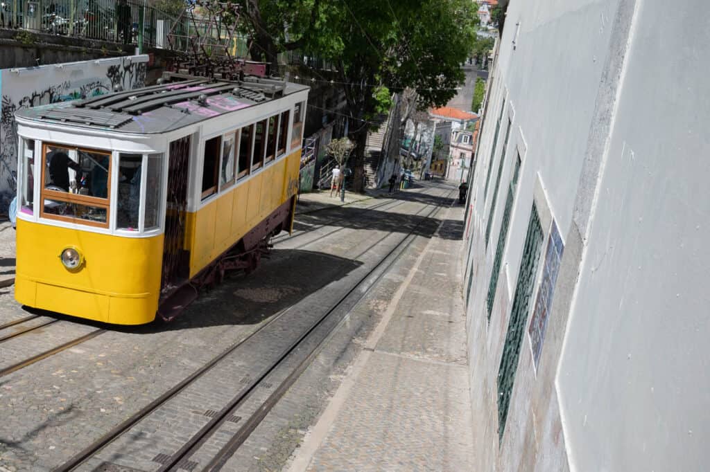 Yellow tram in Lisbon Portugal climbs a hill.
