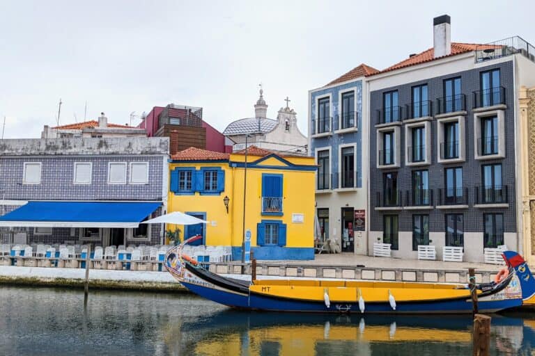 Yellow and blue boat in a canal near a yellow and blue building in Aveiro.