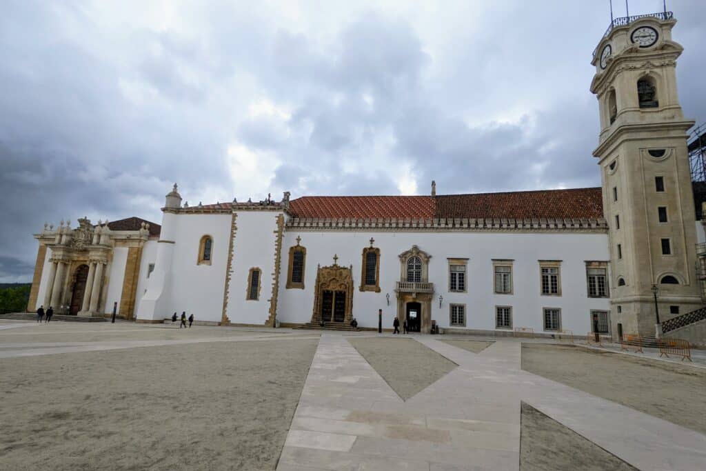 Coimbra University- exterior of the library. White stucco building with brown stone tower and red tile roof.