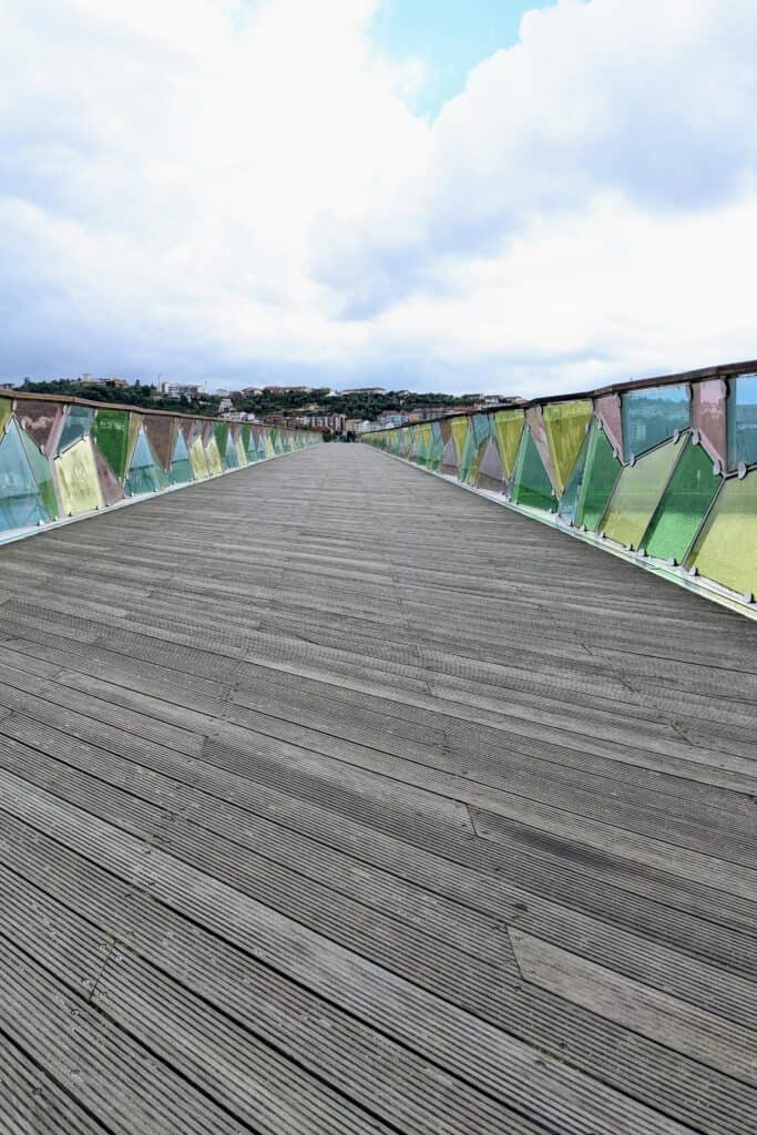 Colorful bridge in Coimbra. Green, Yellow, Pink, and Blue plastic designs line a wood bridge.