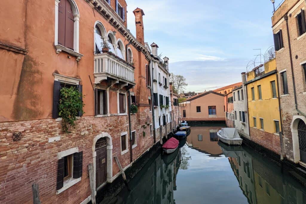 Canal in Venice with orange and yellow buildings on the sides.