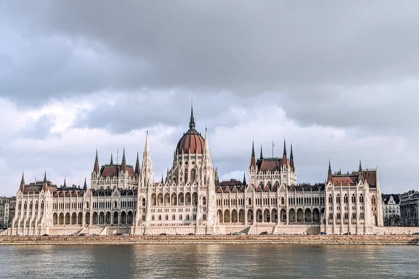 View of Parliament building from the shore across the Danube. The white building with it's red roof towers above the water.