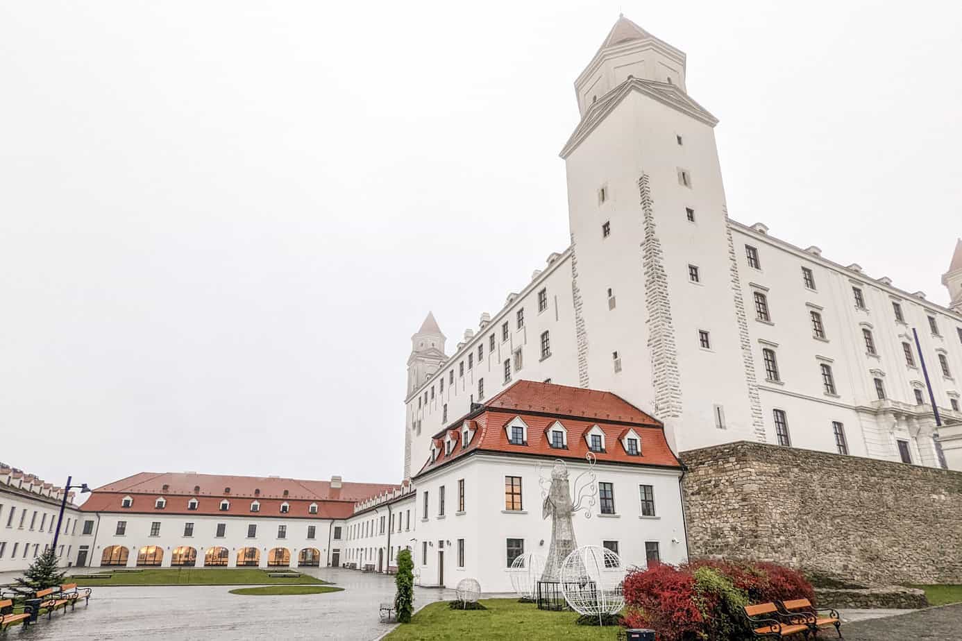 Bratislava castle - white castle with red roof on smaller buildings. Clouded foggy sky overhead