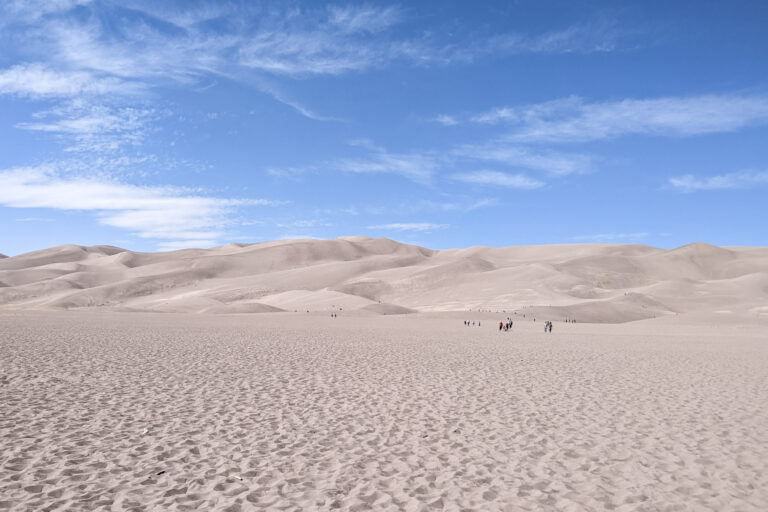 Sand dunes rise with a blue sky behind