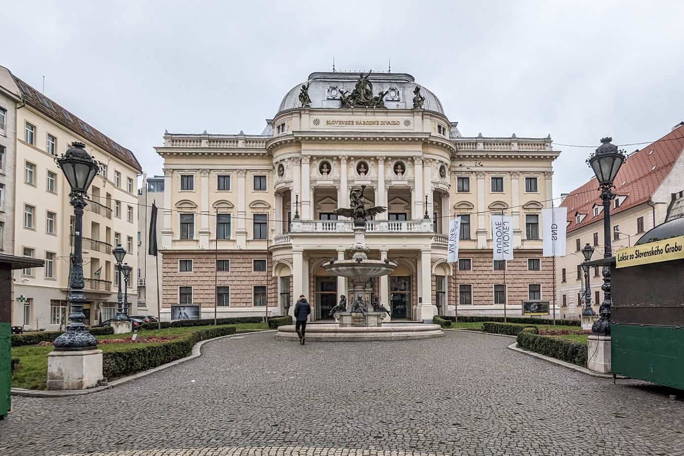 Exterior of Slovak National Theatre with a fountain in front on a cloudy day