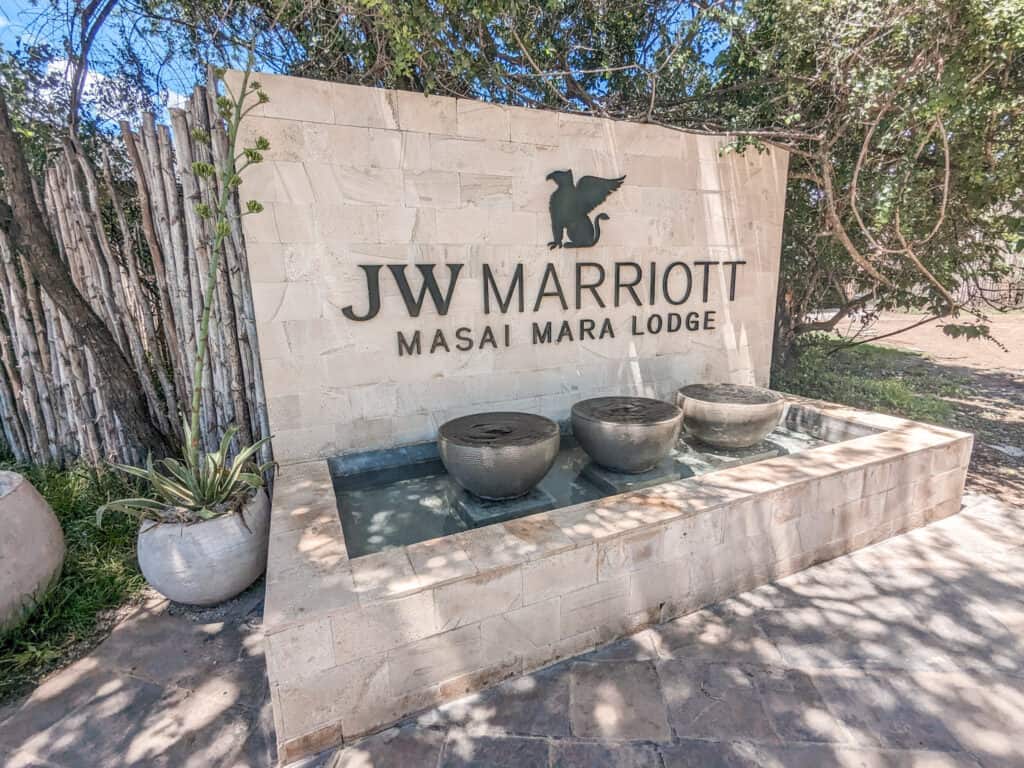 Sign with JW Marriott Masai Mara Lodge and the Marriott logo. With 3 fountains beneath