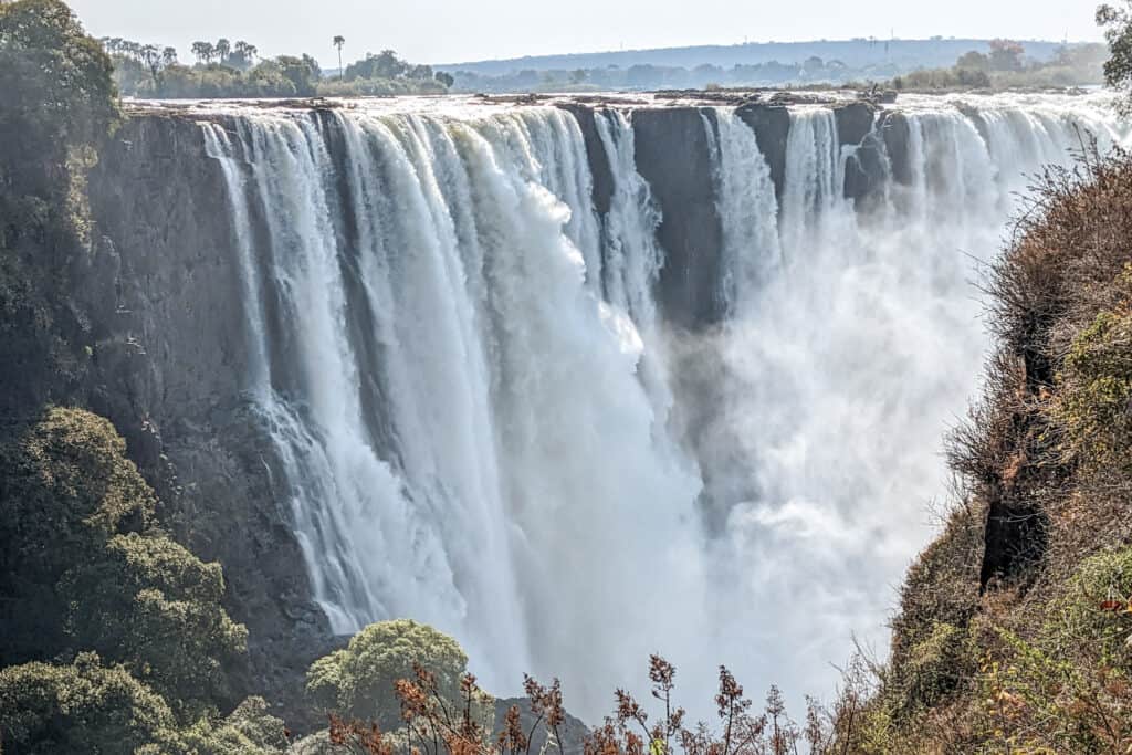 Multiple streams of water cascade down Victoria Falls with mist at the bottom