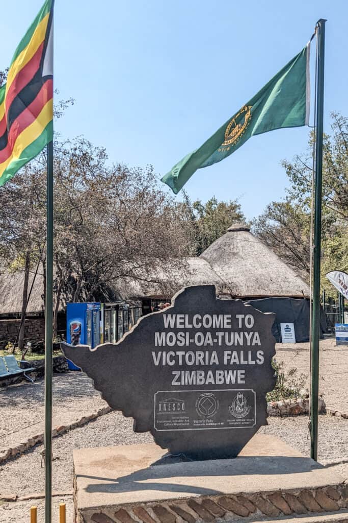 Welcome Sign at Victoria Falls National Park Entrance. A stone reads "Welcome to Mosi-oa-tunya Victoria Falls Zimbabwe"